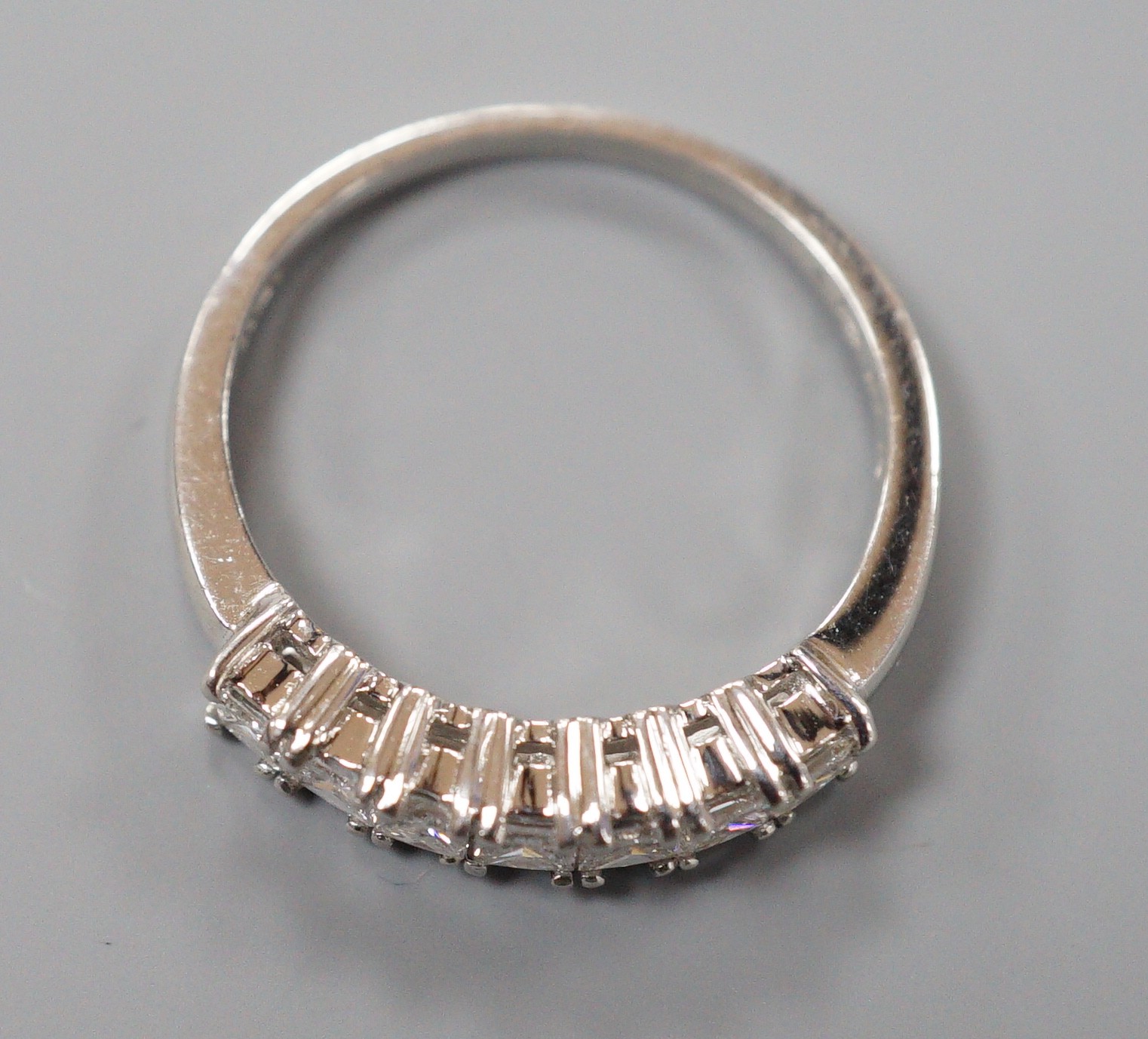 A modern platinum and seven stone princess cut diamond set half hoop ring, size M/N, gross weight 4 grams